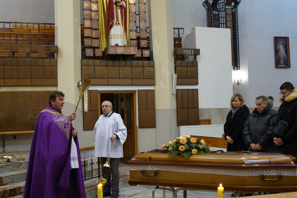 Ksiądz święcący trumnę