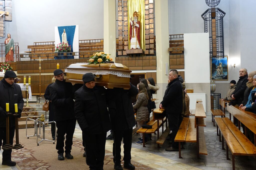 Żałobnicy niosący trumnę