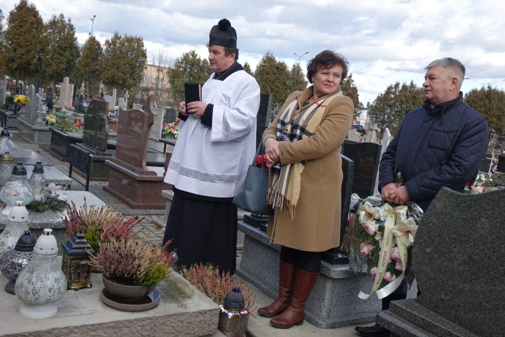 Ksiądz modlący się na cmentarzu